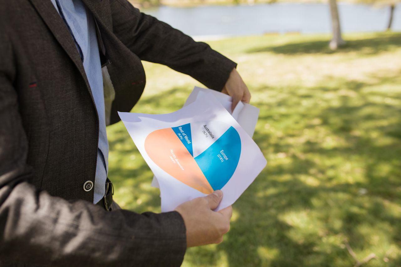 contact-img A business professional holds a printed chart in an outdoor setting, illustrating data insights and analysis.